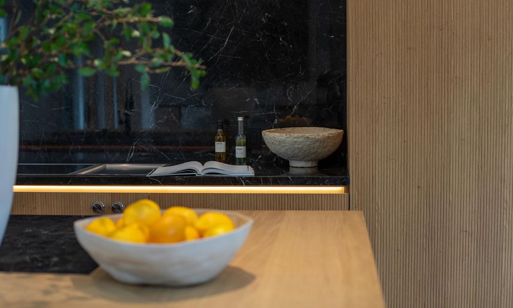 Kitchen island with a bowl of lemons and background counter featuring open cookbook and decorative accents