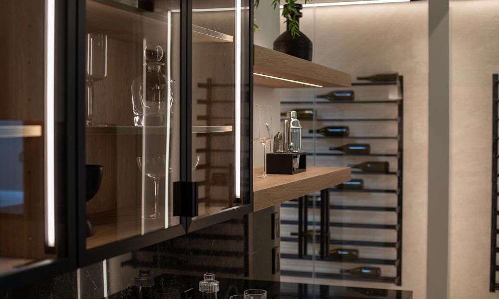 Detailed side view of illuminated bar shelving and glass-front cabinets next to a wine display